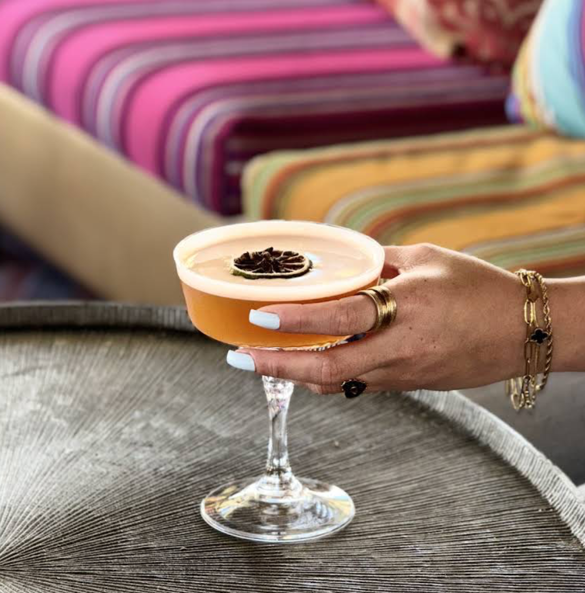 Signature cocktail served beside striped rooftop seating